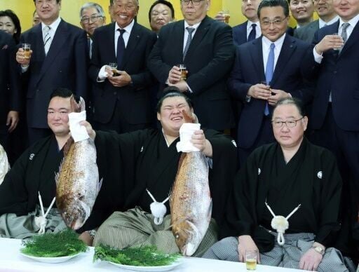Onosato (centre) holds up a fish as to celebrate being promoted to sumo "yokozuna" or grand champion on Wednesday